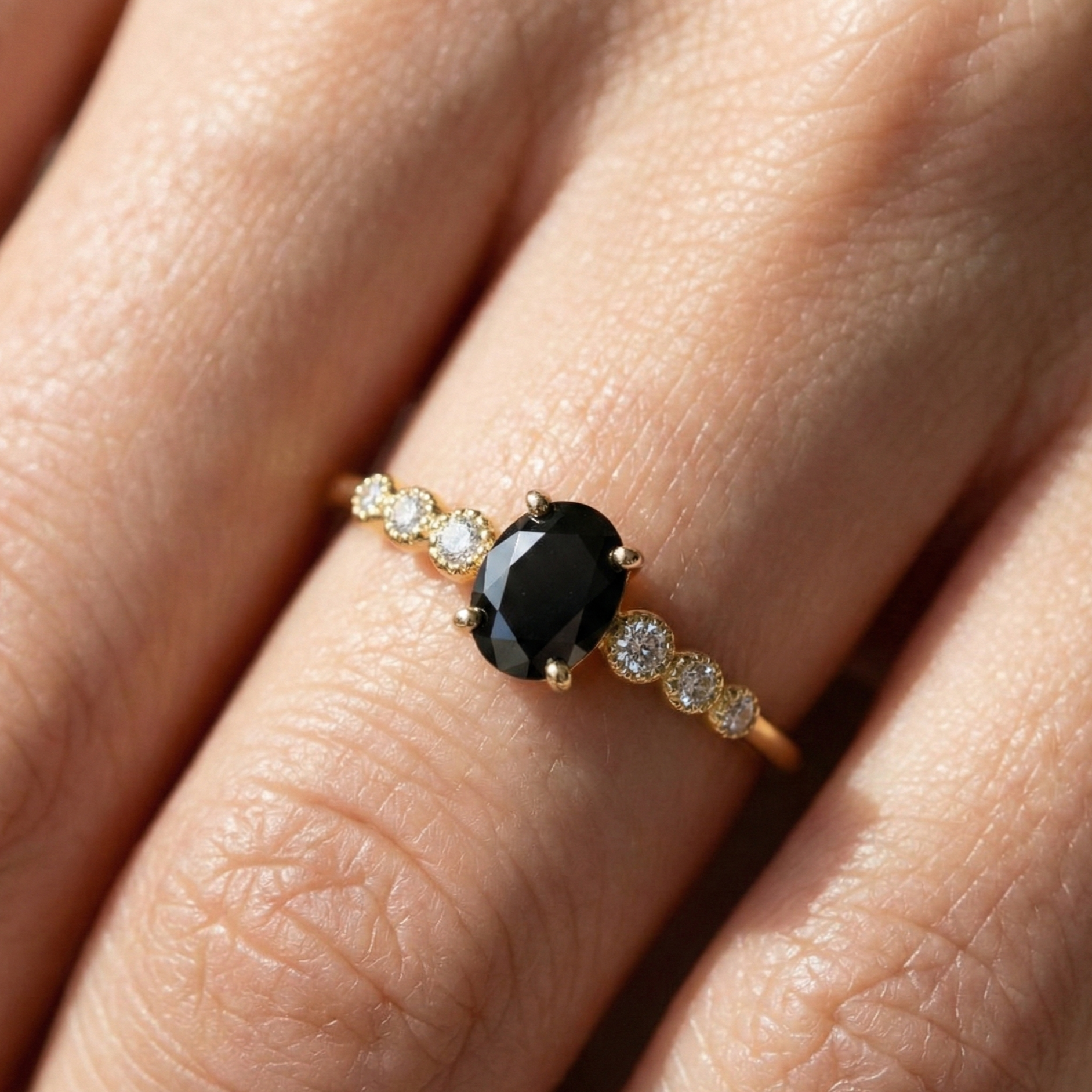 Gold ring with a black black on a person's finger