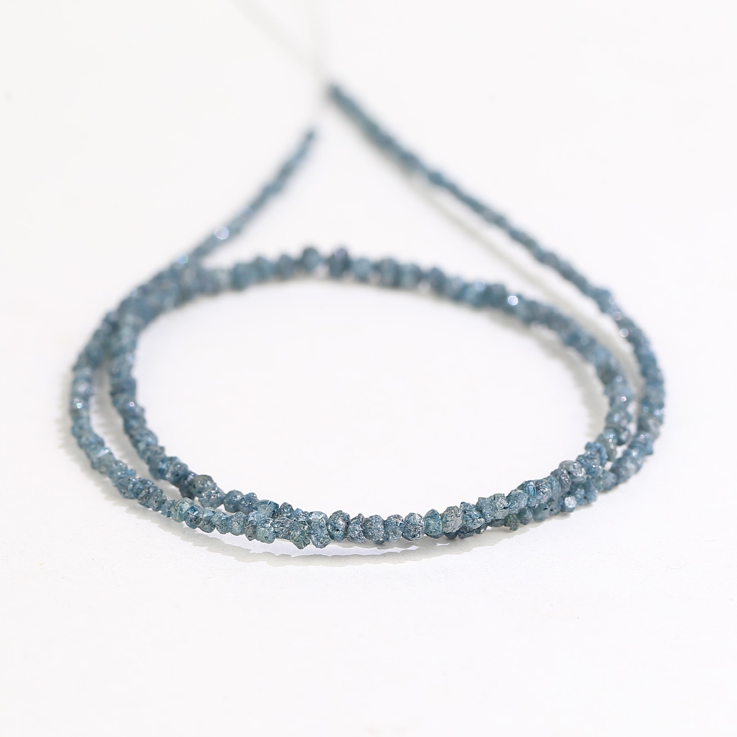 Close-up of a string of small blue beads on a white background