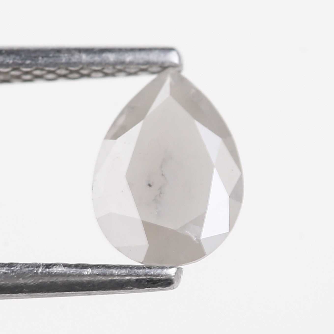 Clear crystal stone held between two metal prongs on a white background