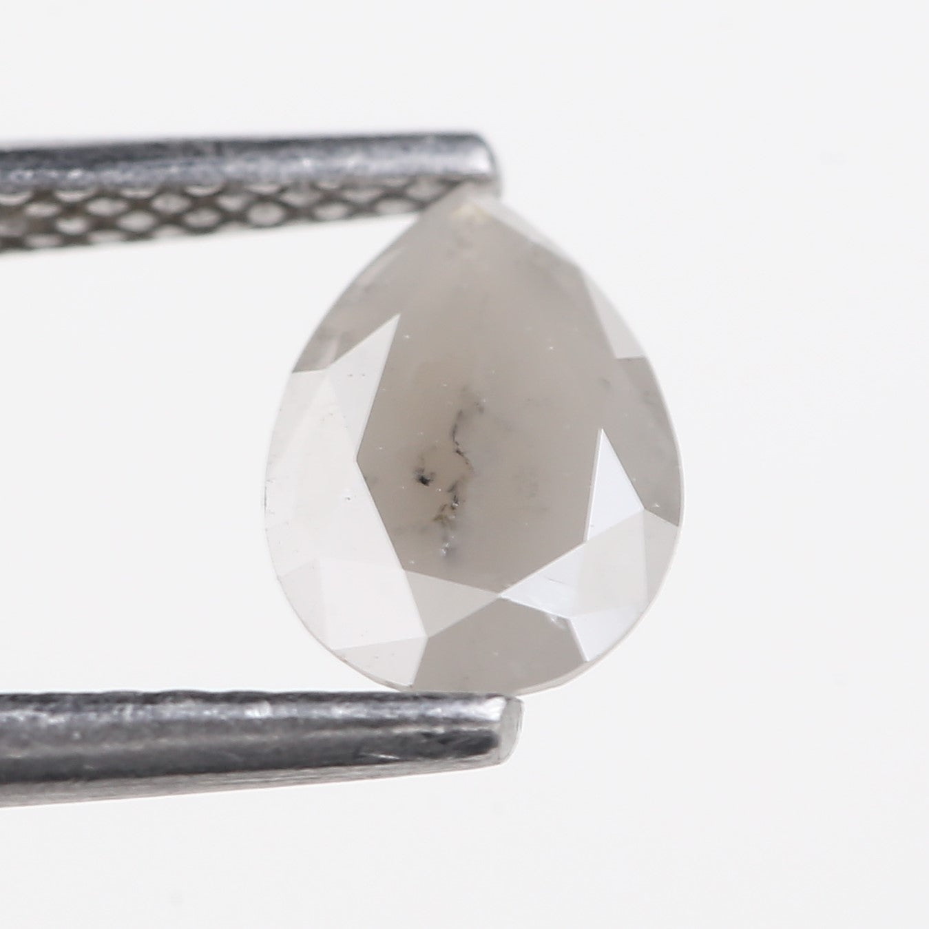 Clear teardrop-shaped gemstone held by tweezers on a white background