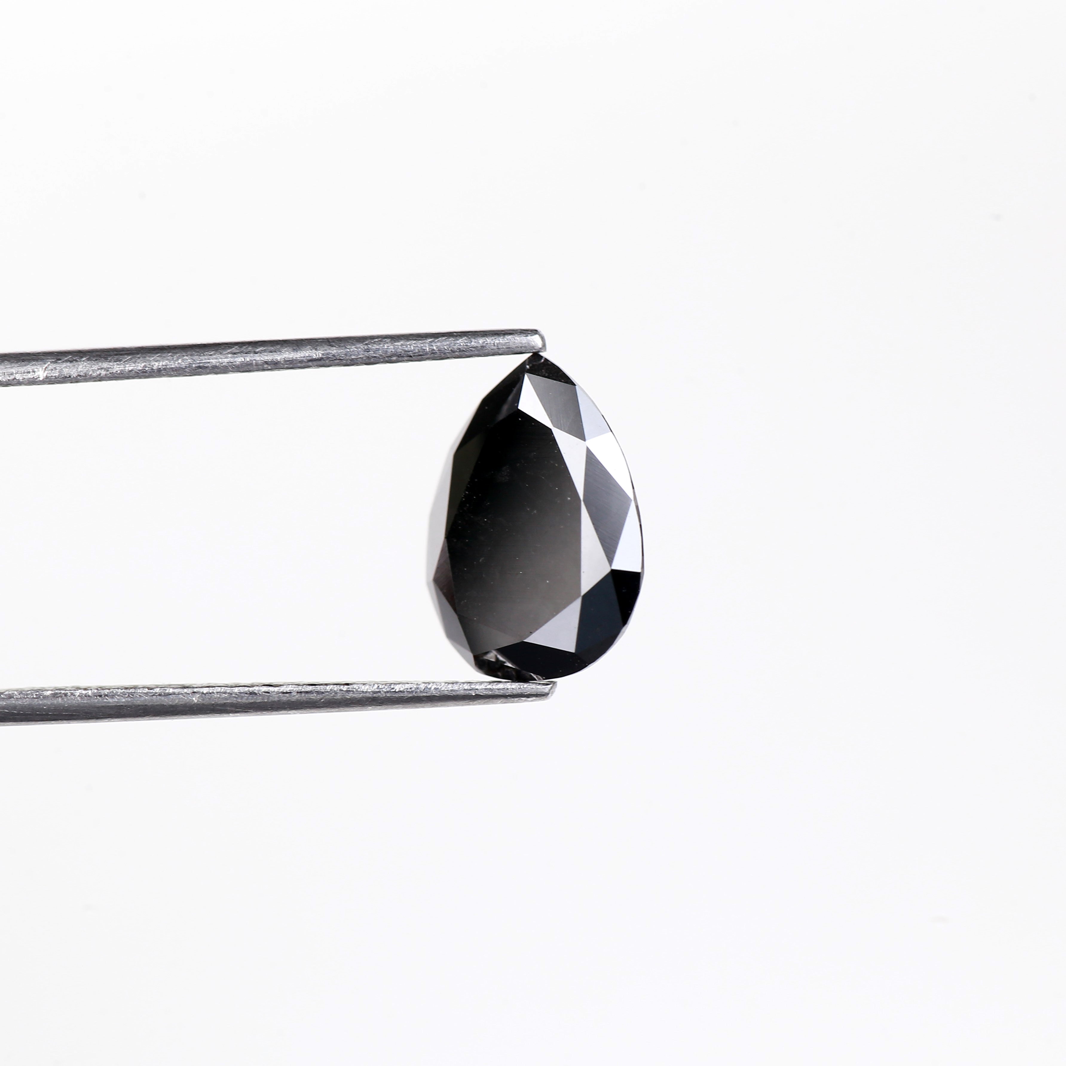 Teardrop-shaped black diamond held by tweezers on a white background