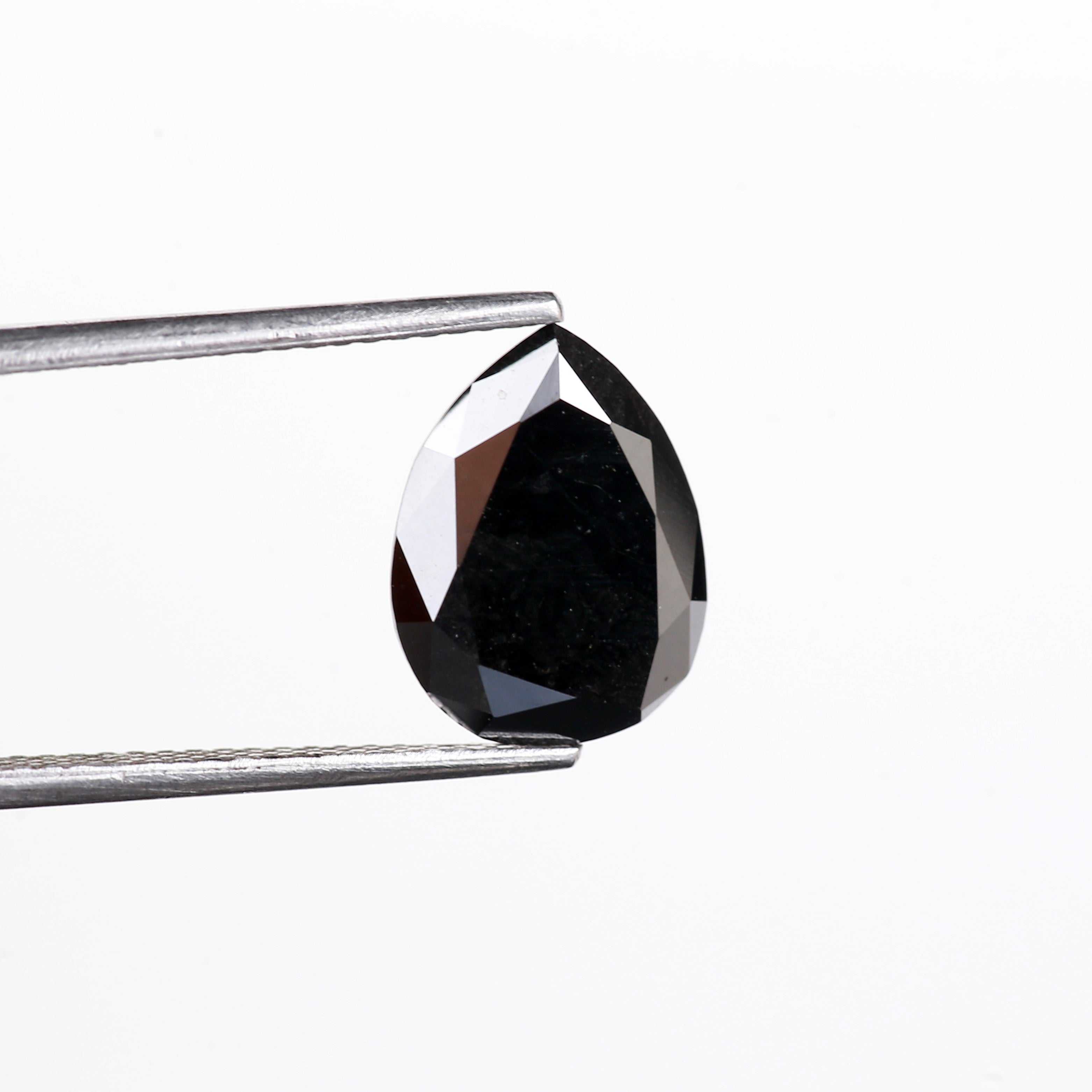Teardrop-shaped black diamond held by tweezers on a white background