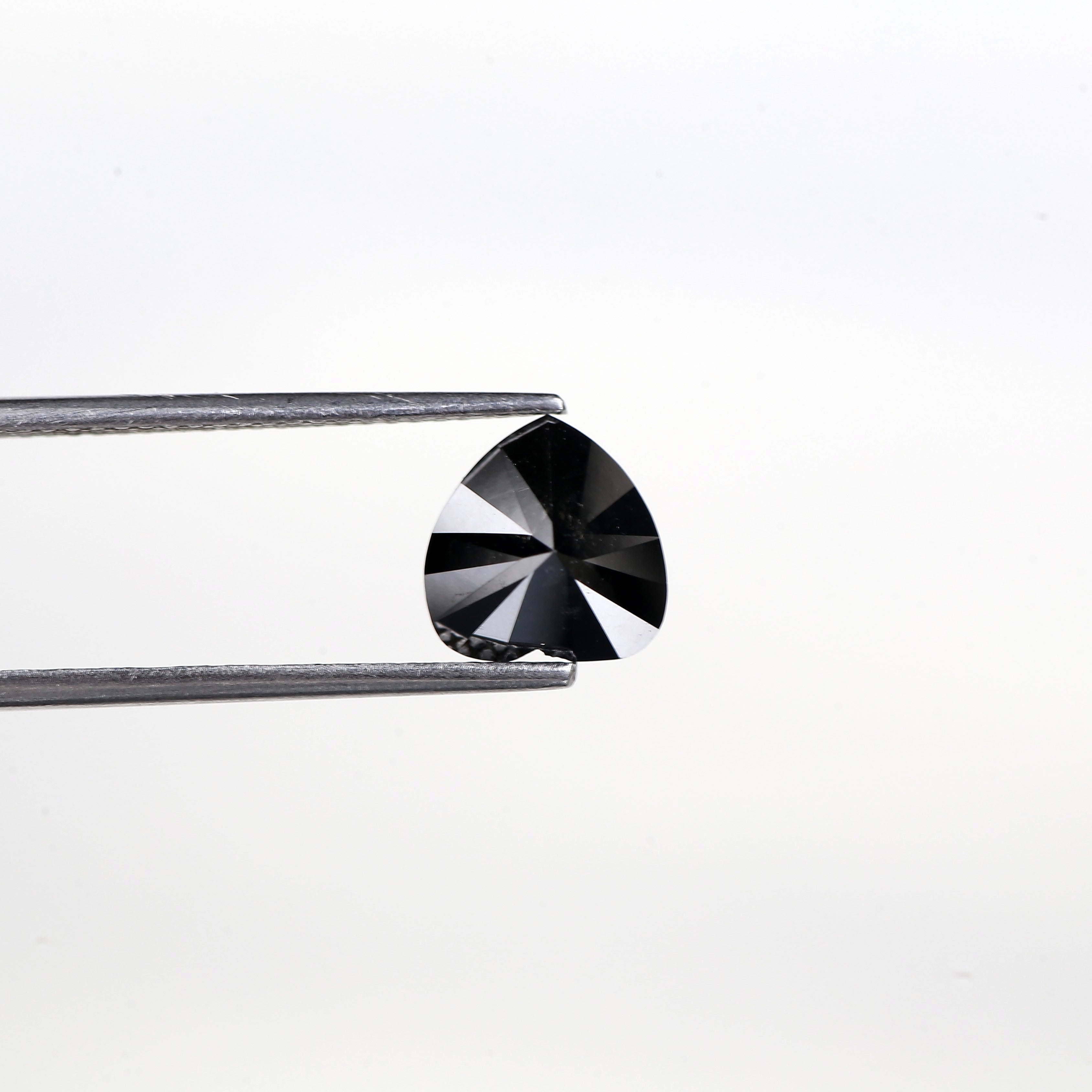 Black diamond held by tweezers on a white background