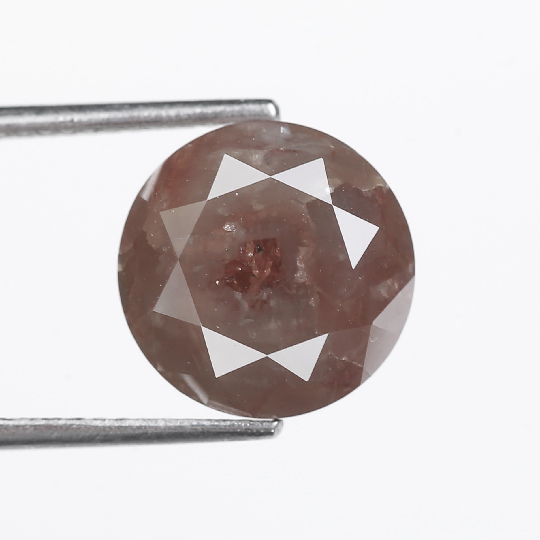 Brown diamond held between tweezers on a white background
