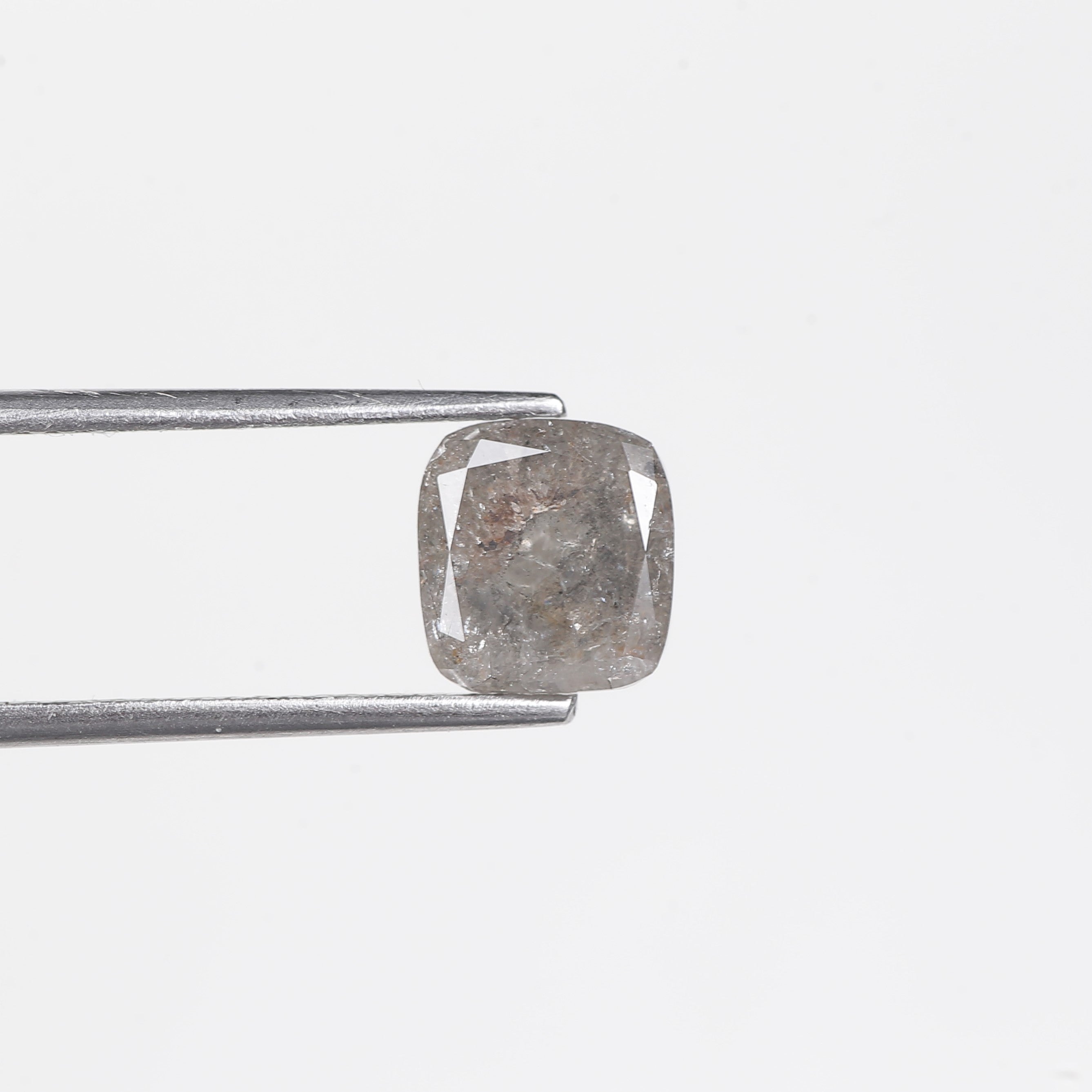 Diamond held between tweezers on a light gray background