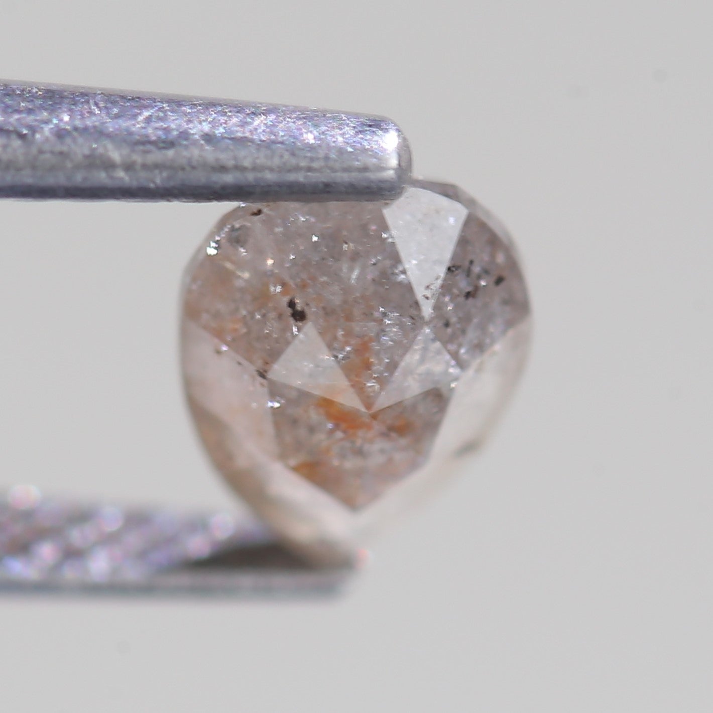 Diamond held by tweezers against a neutral background