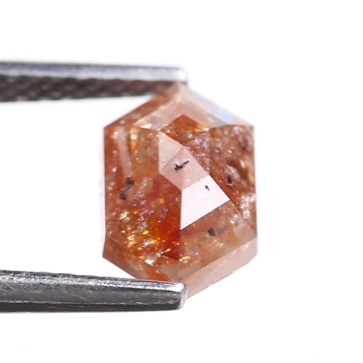 Hexagonal orange diamond held by tweezers on a white background