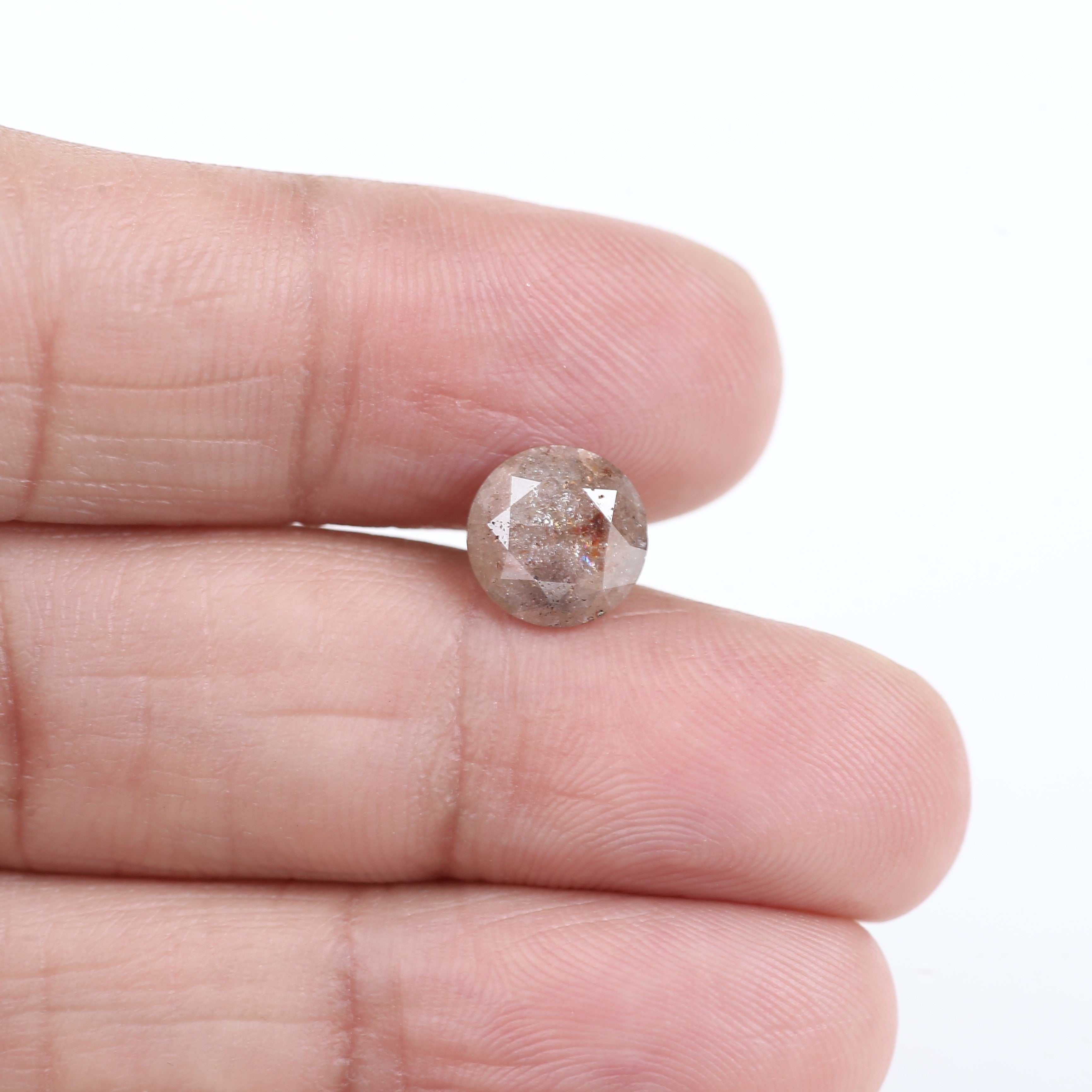 Diamond held between fingers on a white background