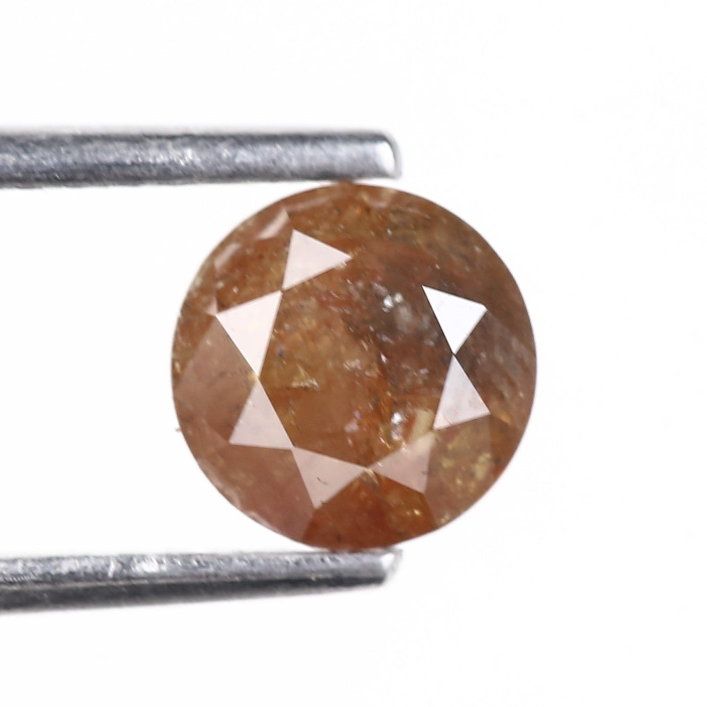 Brown diamond held by tweezers on a white background