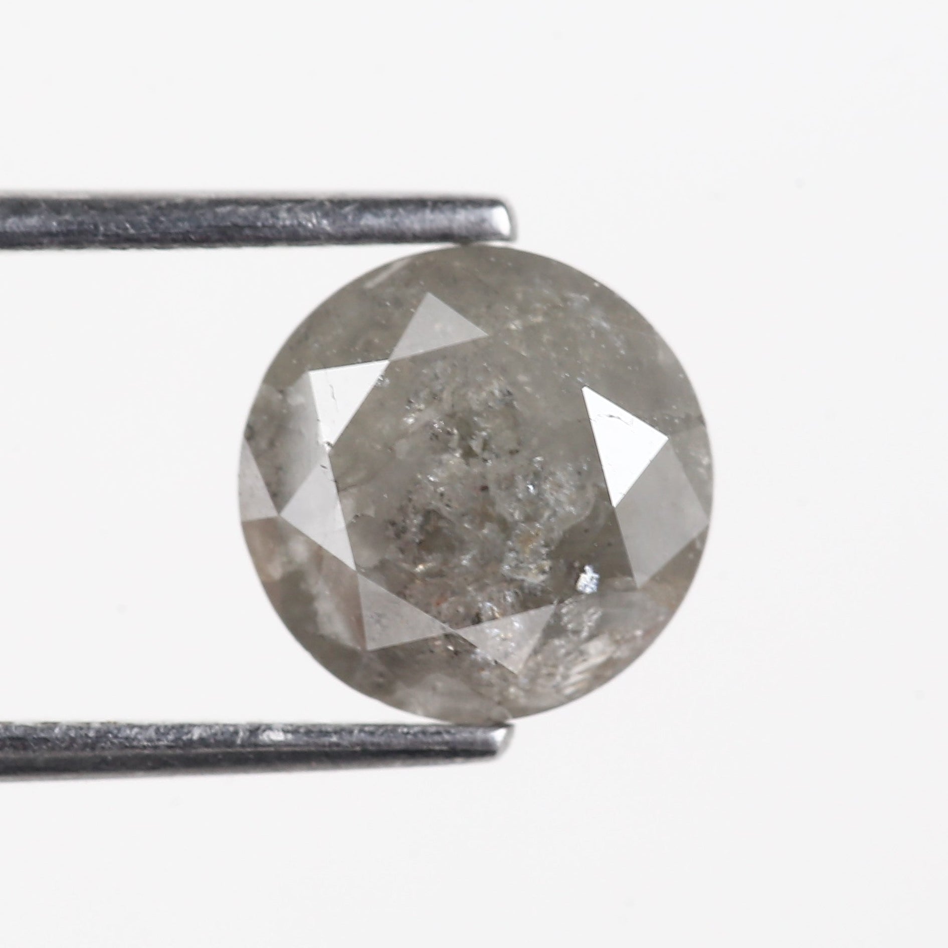 Round diamond held between tweezers on a white background