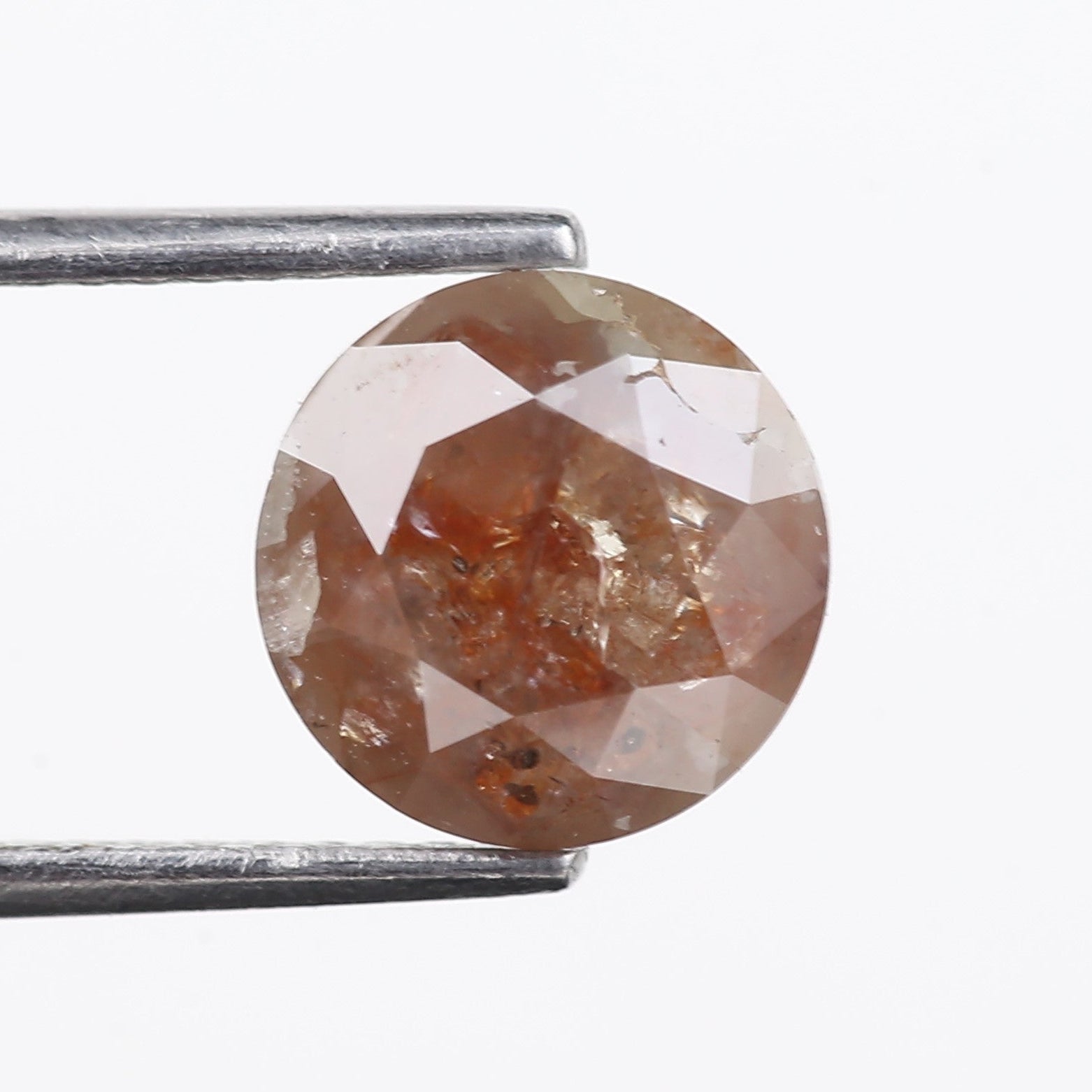 orange diamond held by tweezers on a white background