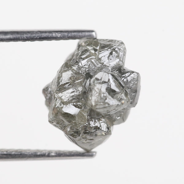 Raw diamond held by tweezers on a white background