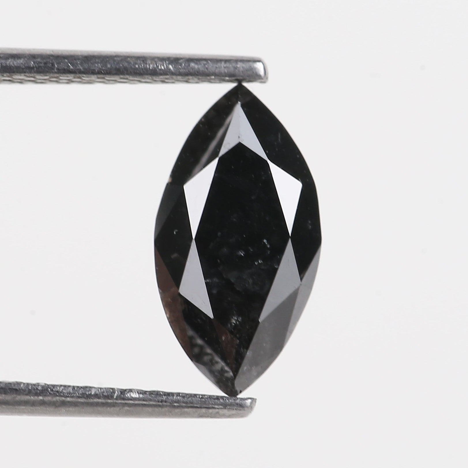 Black diamond held by tweezers on a white background