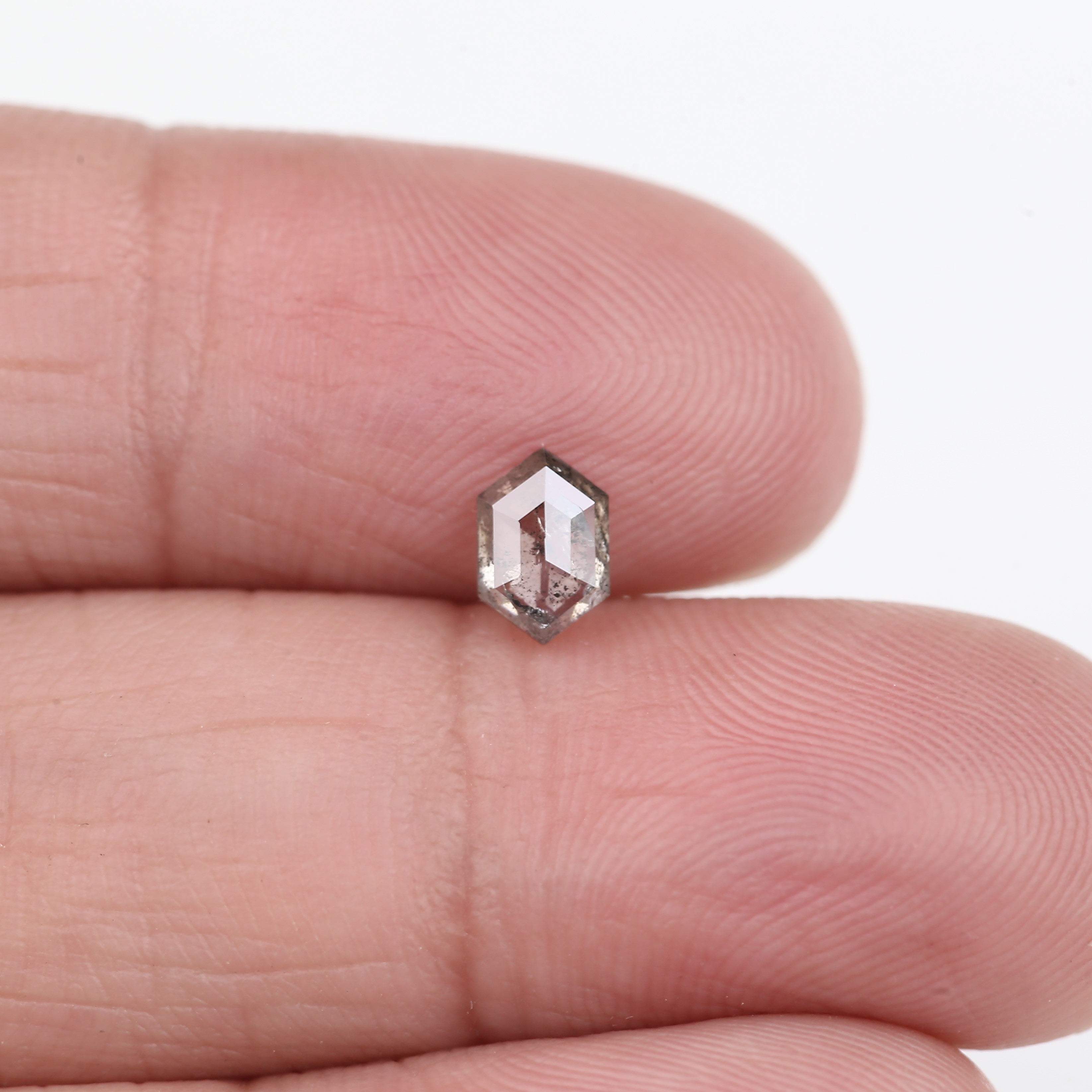 Hexagonal diamond held between fingers against a white background