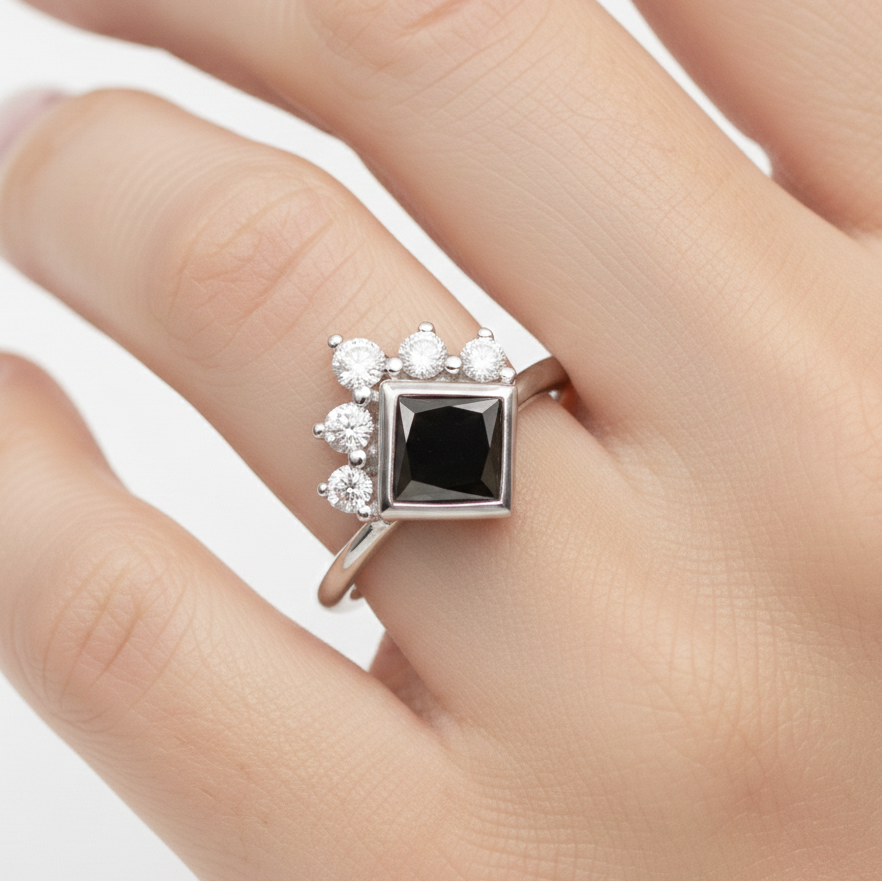 white gold ring with a black diamond on a finger against a white background