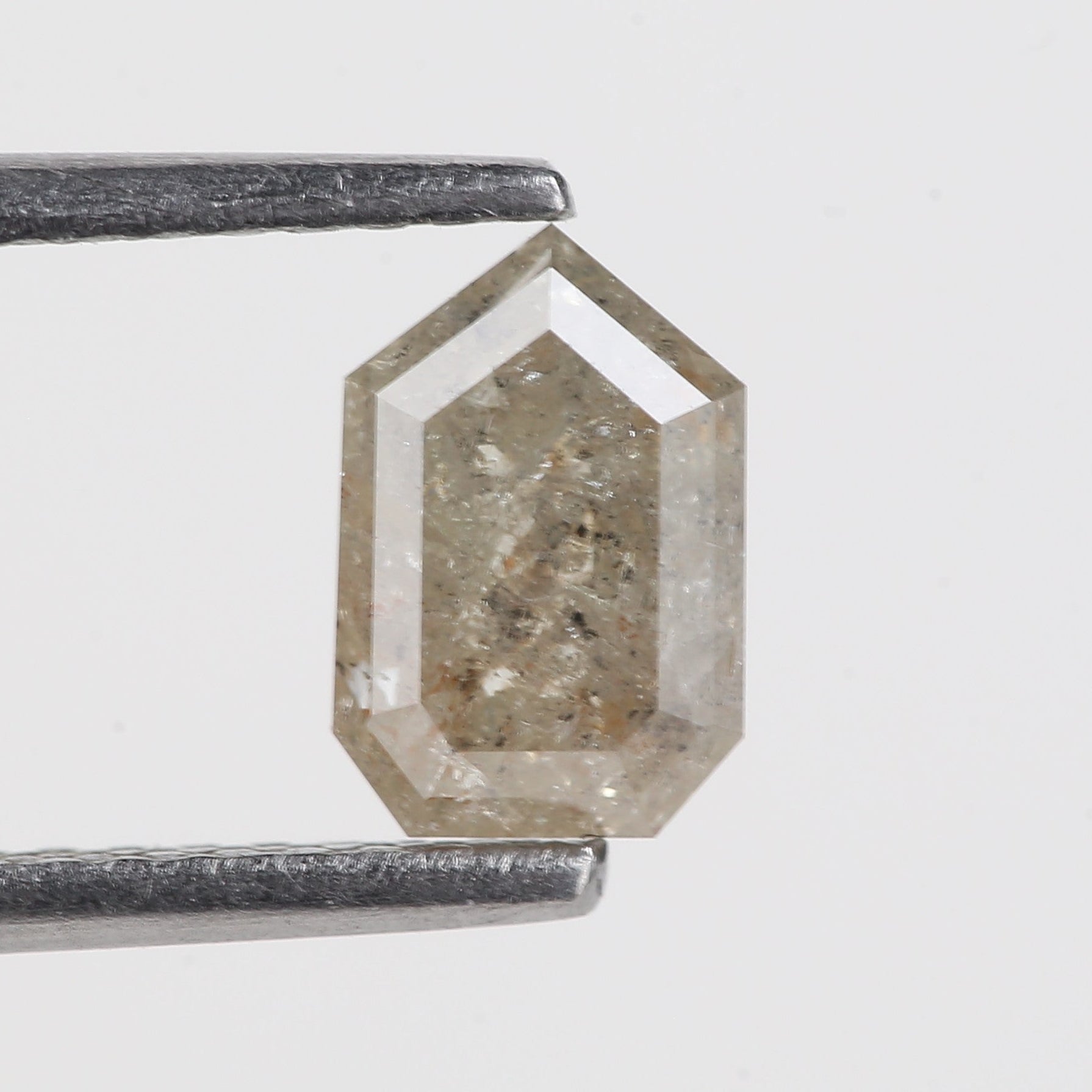 Hexagonal crystal held by tweezers on a light gray background
