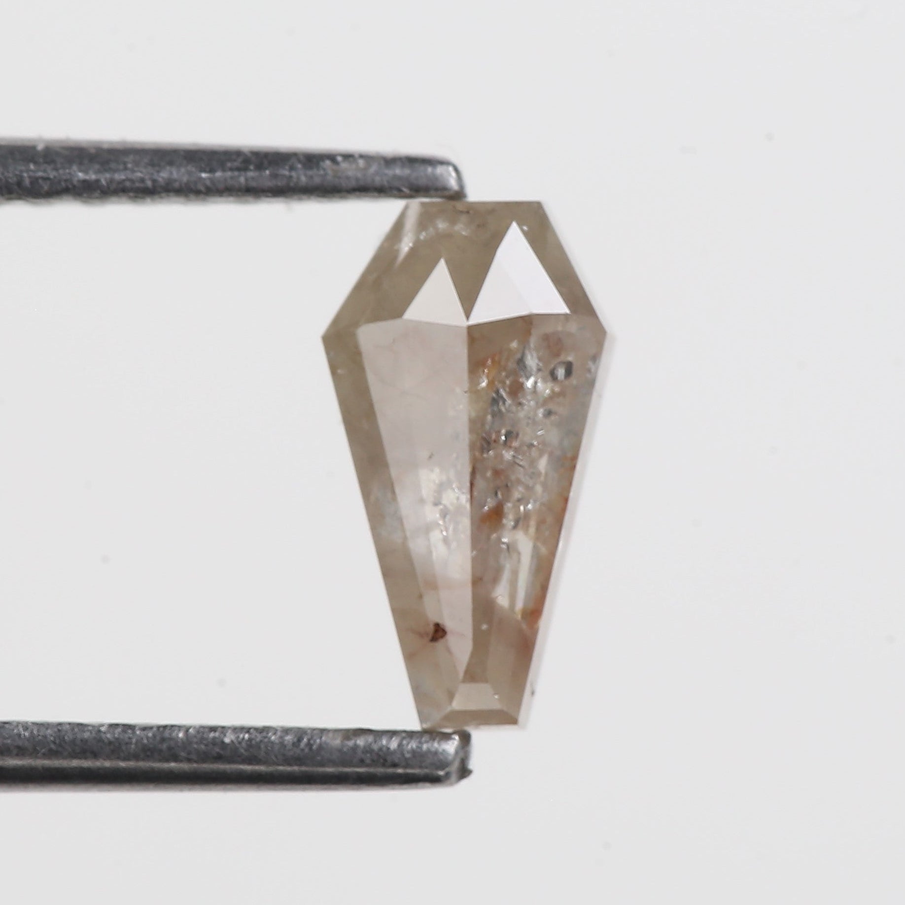 Coffin shield Crystal pendant held by tweezers on a light gray background