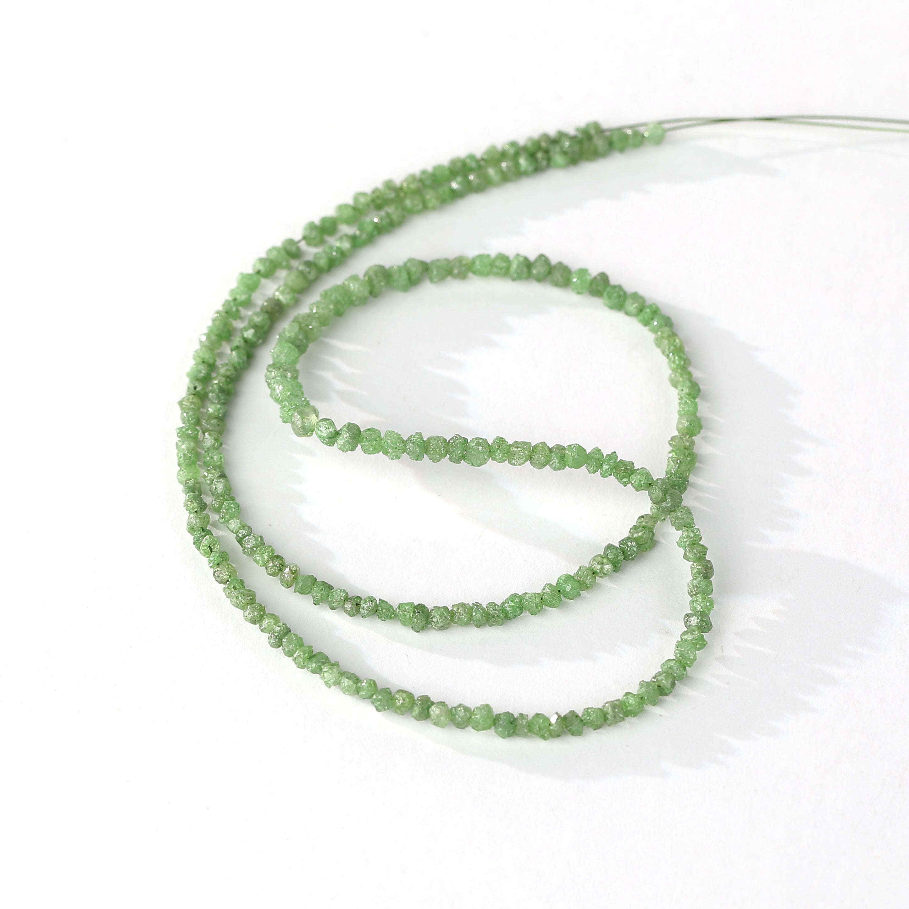 Emerald green rough diamond beads strand on white background
