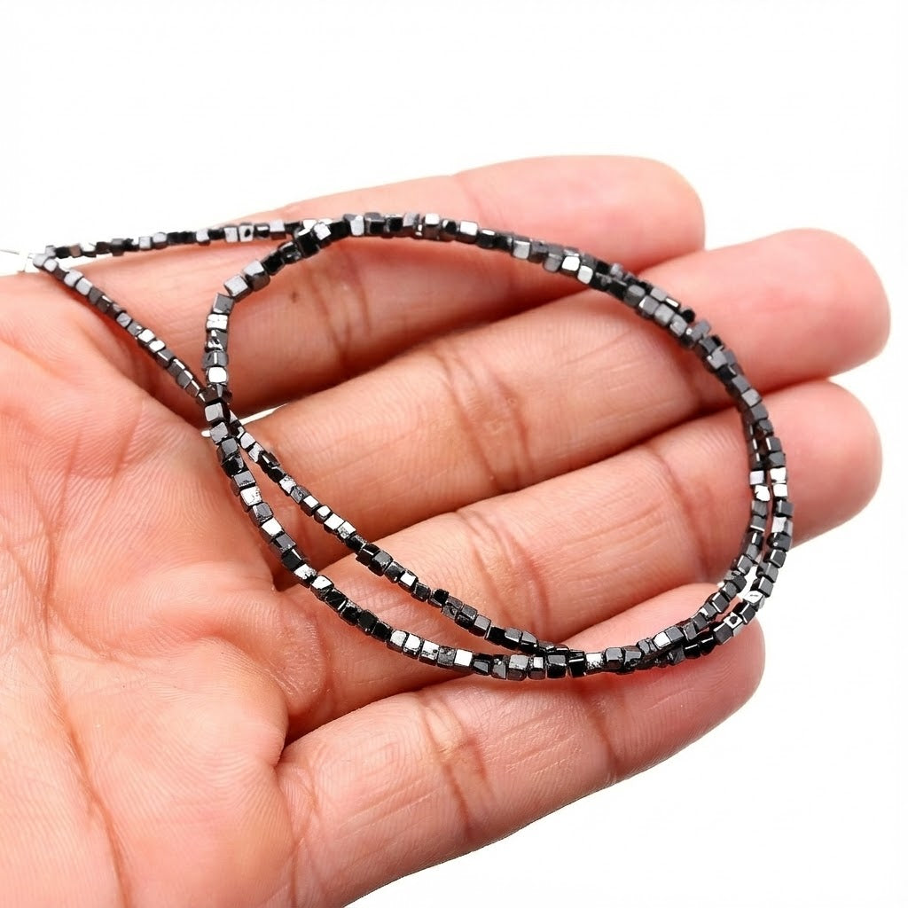 Black beaded necklace held in a hand against a white background