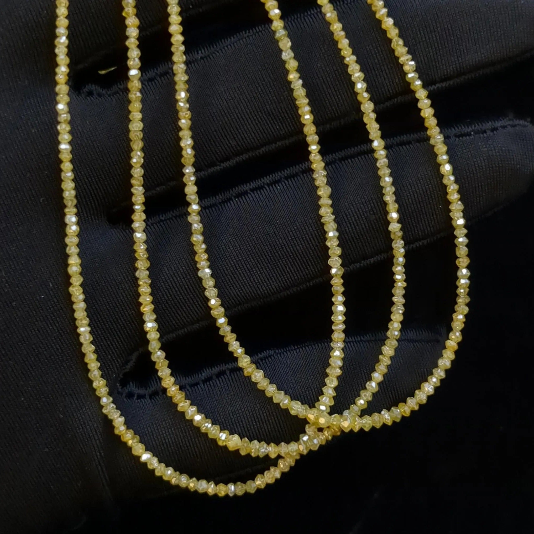 Three strands of small yellow beads on a black background