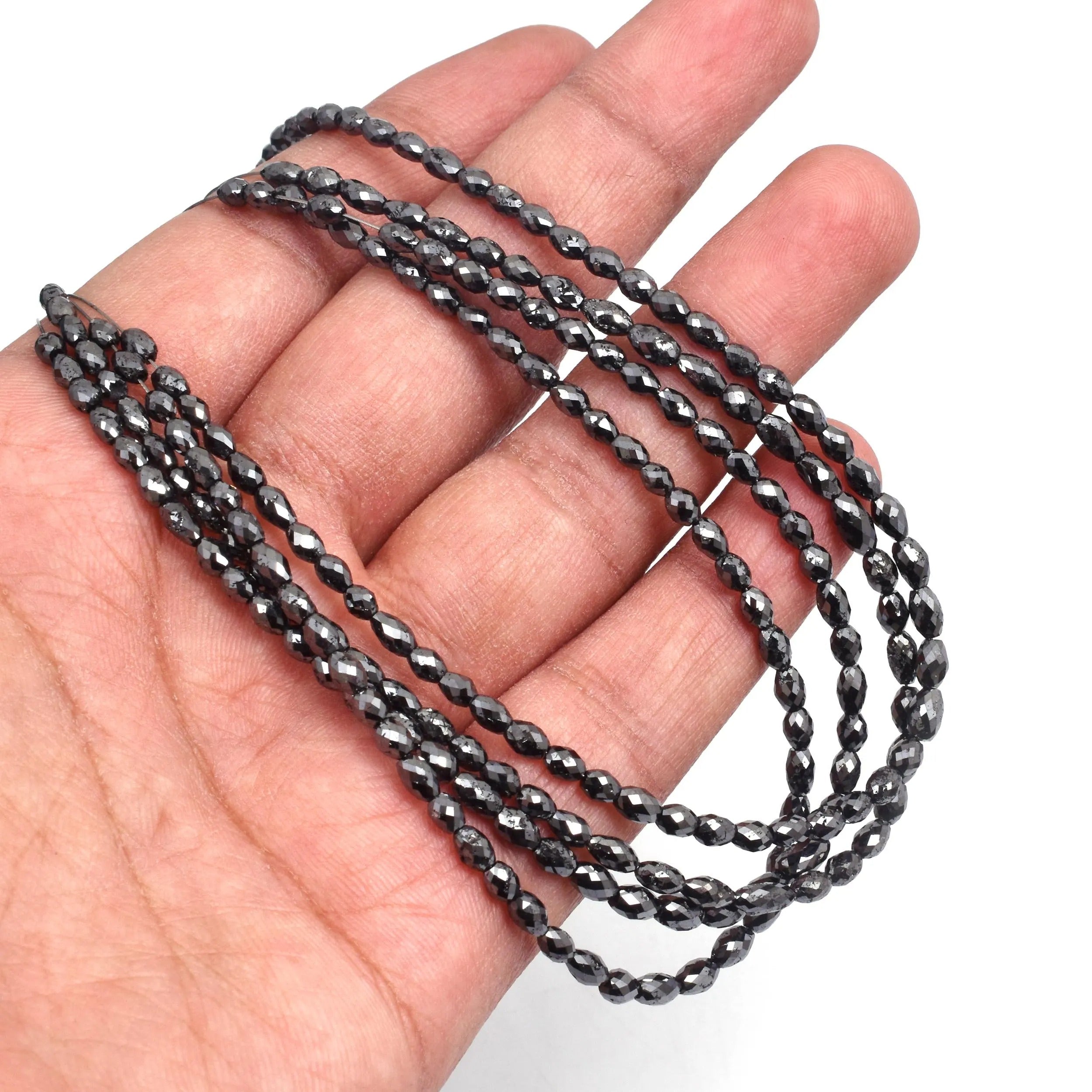 Black beaded chain held in a hand against a white background