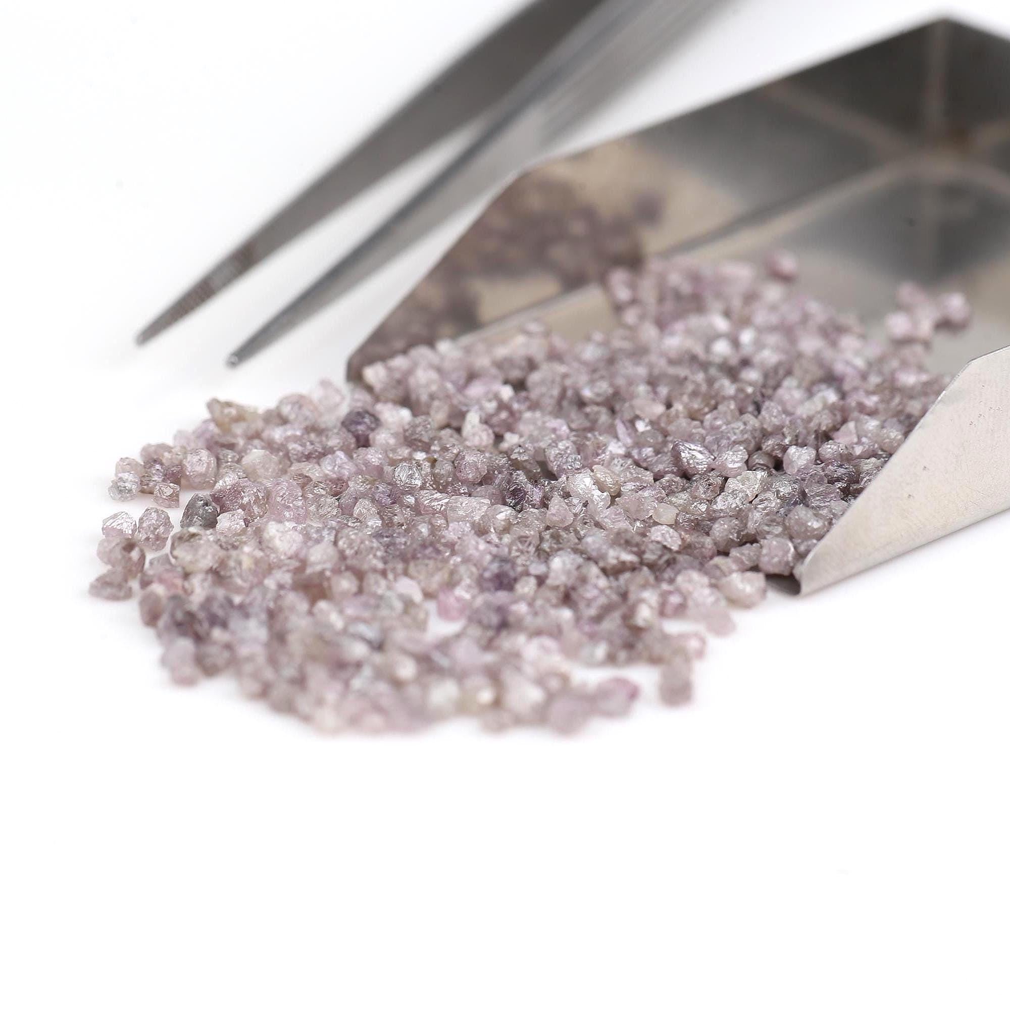 Small pile of pinkish crystals with tweezers on a white background