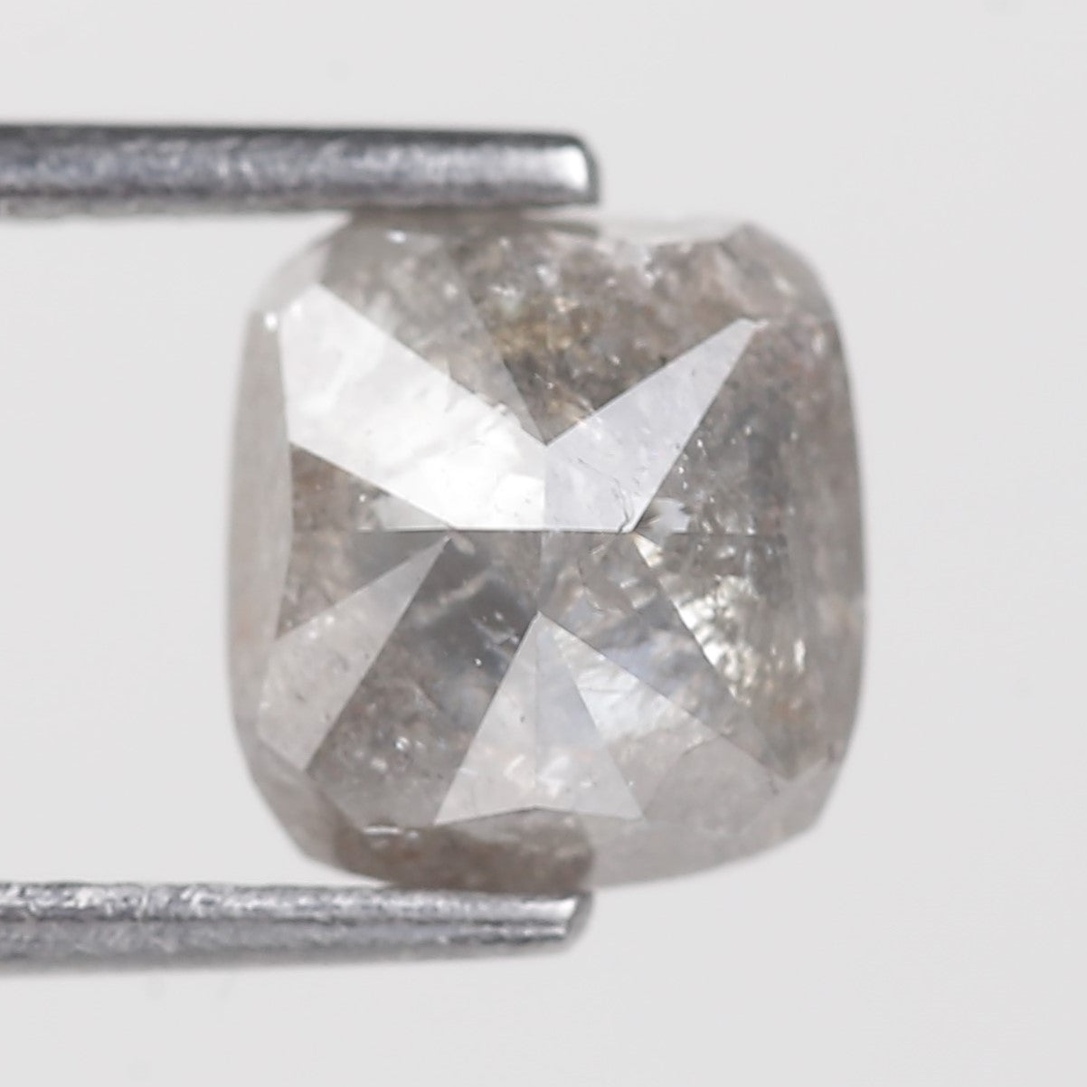 Square-cut diamond held by a pair of tweezers on a white background