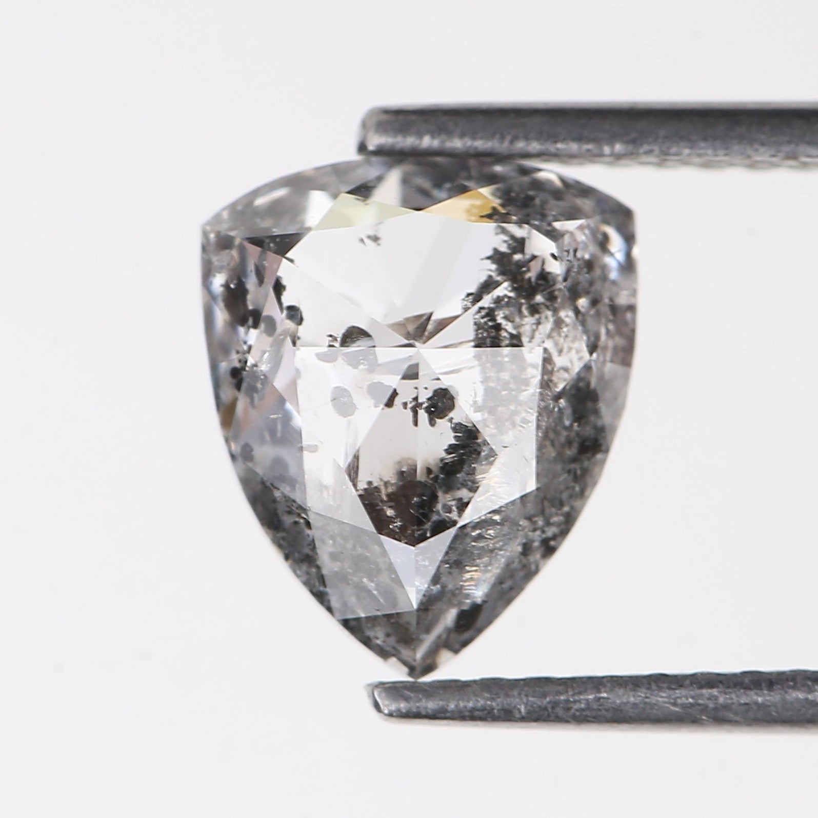 Teardrop-shaped diamond held by tweezers on a light gray background